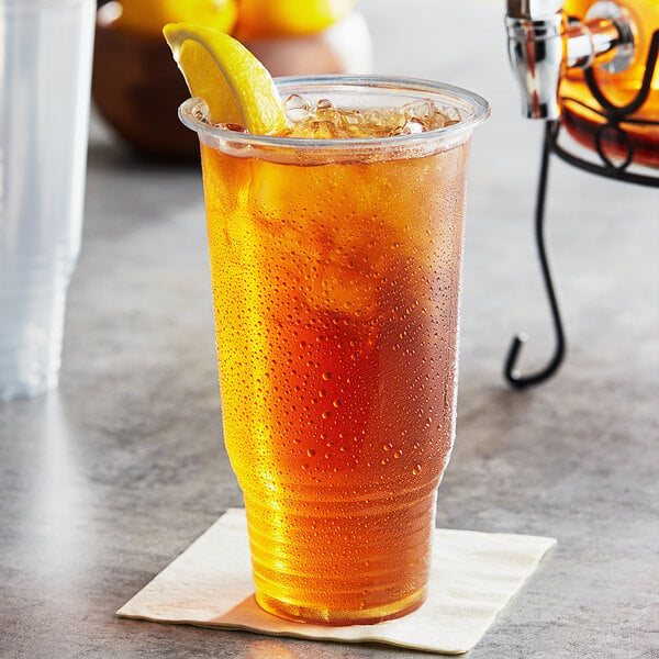 A clear Choice HD plastic cup of iced tea with a lemon wedge.