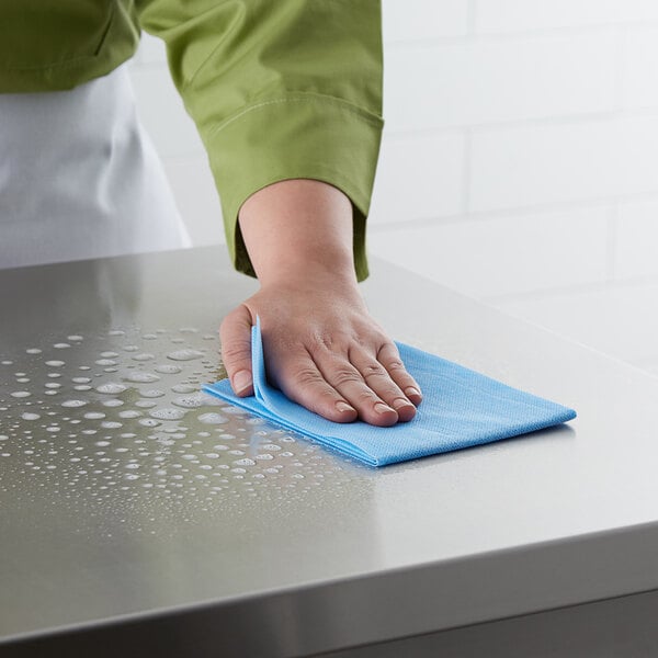 A person cleaning a surface with a blue ChoiceHD foodservice wiper.