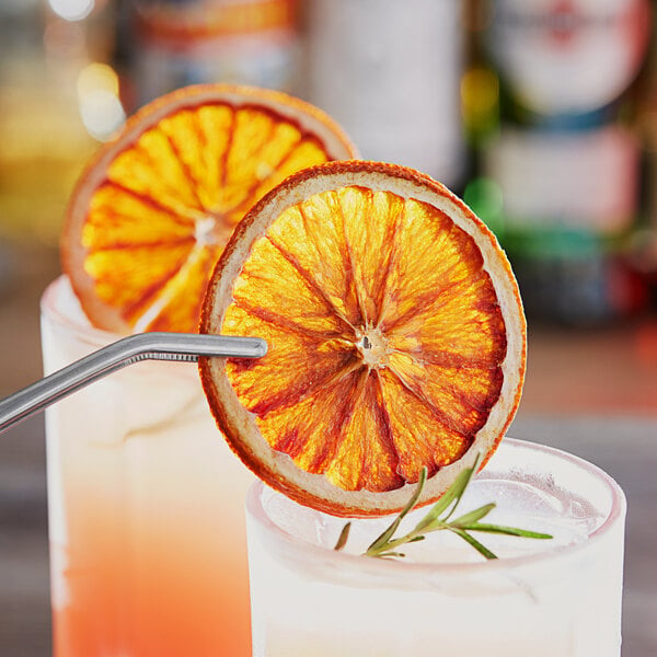 A close up of two glasses with a straw and Blue Henry dried blood orange slices on them.