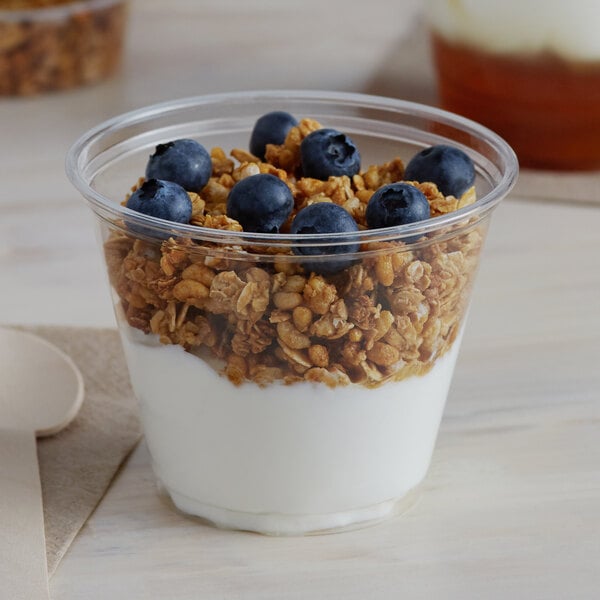 A Solo clear plastic cup filled with yogurt, granola, and blueberries.