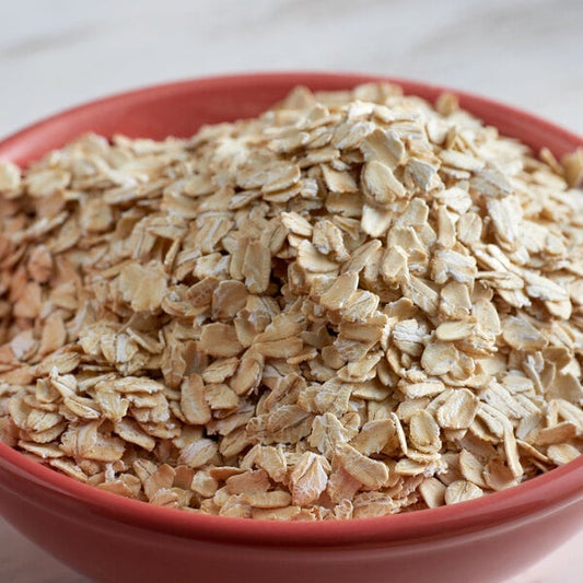 A bowl of Bob's Red Mill gluten-free whole grain oat flakes on a table.