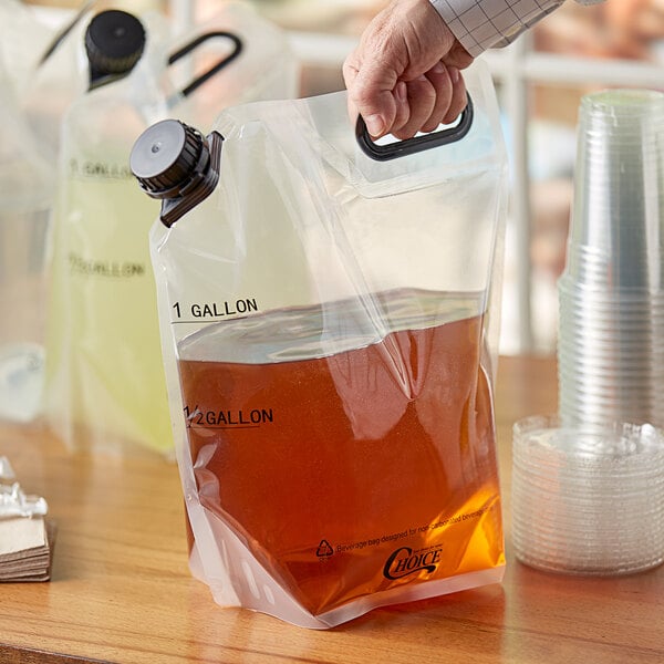 A hand holding a plastic bag of brown liquid with a cap.