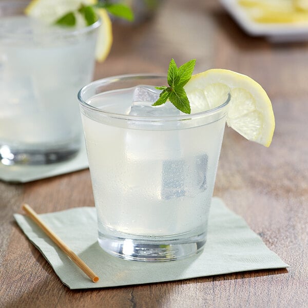 A glass of Del Destino lemon juice with ice and a lemon wedge.
