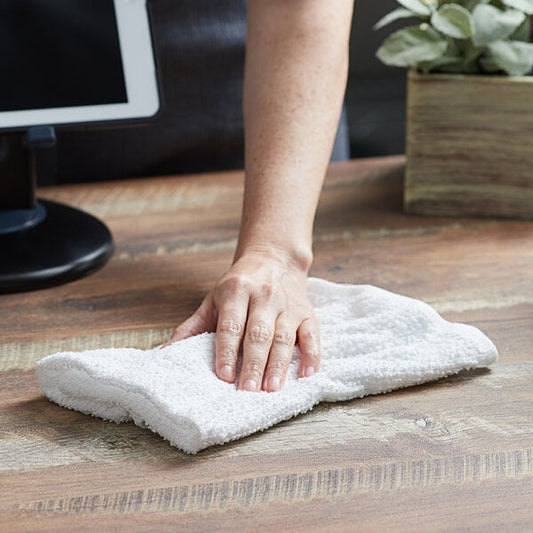 A hand wiping a surface with a white Choice terry bar towel.
