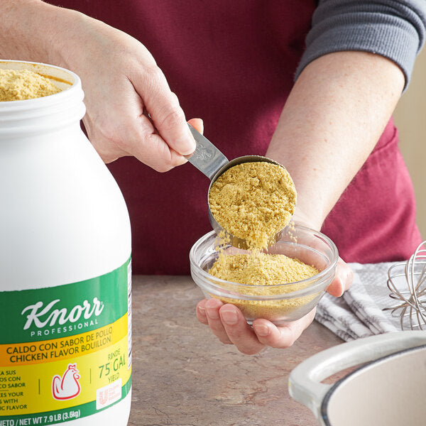 A person pouring yellow powder from a green and white jar into a bowl.