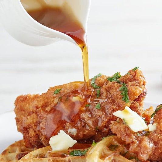 A plate of chicken and waffles with Butternut Mountain Farm Grade A Dark Pure Vermont Maple Syrup on top.