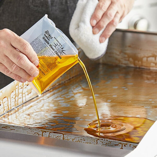A person pouring a liquid from a packet onto a grill.