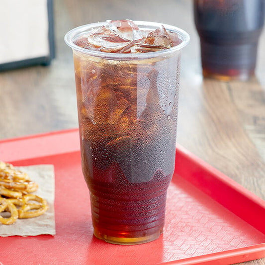 A plastic cup with a clear drink and a straw on a red tray.