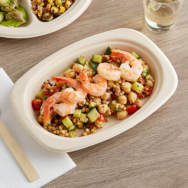 A World Centric compostable fiber plate of food with a salad on a table.