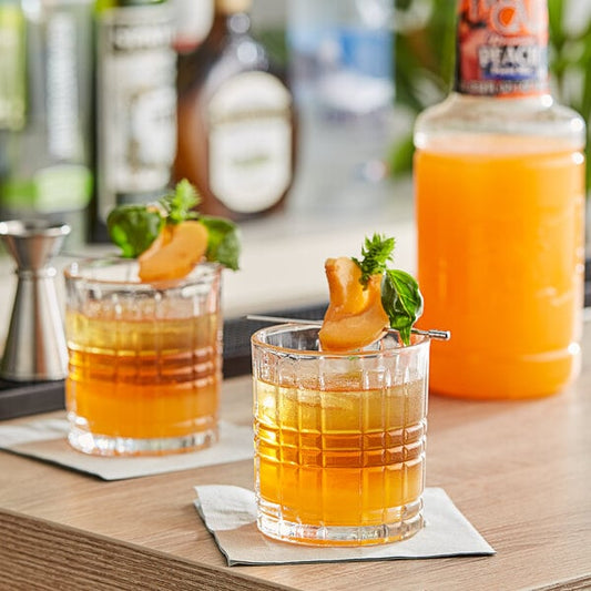 Two glasses of Finest Call peach drinks on a table.