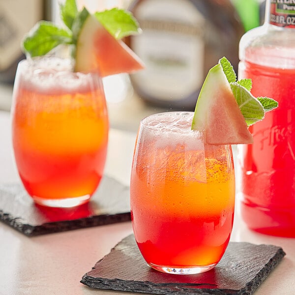 Two glasses of Finest Call watermelon cocktail with a slice of watermelon on top of one.