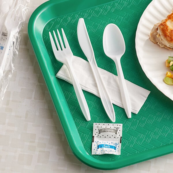A green tray with a white plastic fork, spoon, and knife.