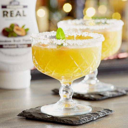 Two glasses of yellow liquid on a table with Real Passion Fruit Puree Infused Syrup drinks.