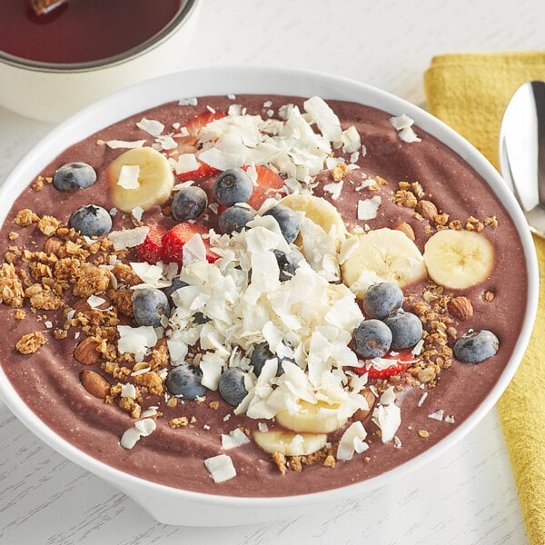 A bowl of chocolate smoothie with Bob's Red Mill Unsweetened Coconut Flakes on top.