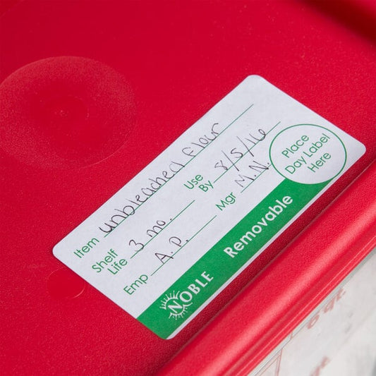 A red Noble Products food container with a removable day label on it.